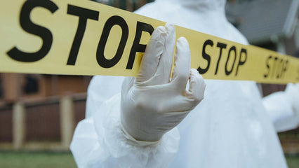 an investigator wearing gloves while holding a yellow police stop tape