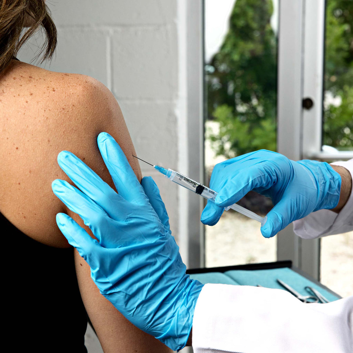 a doctor giving an IM injection to a patient while wearing exam grade nitrile gloves