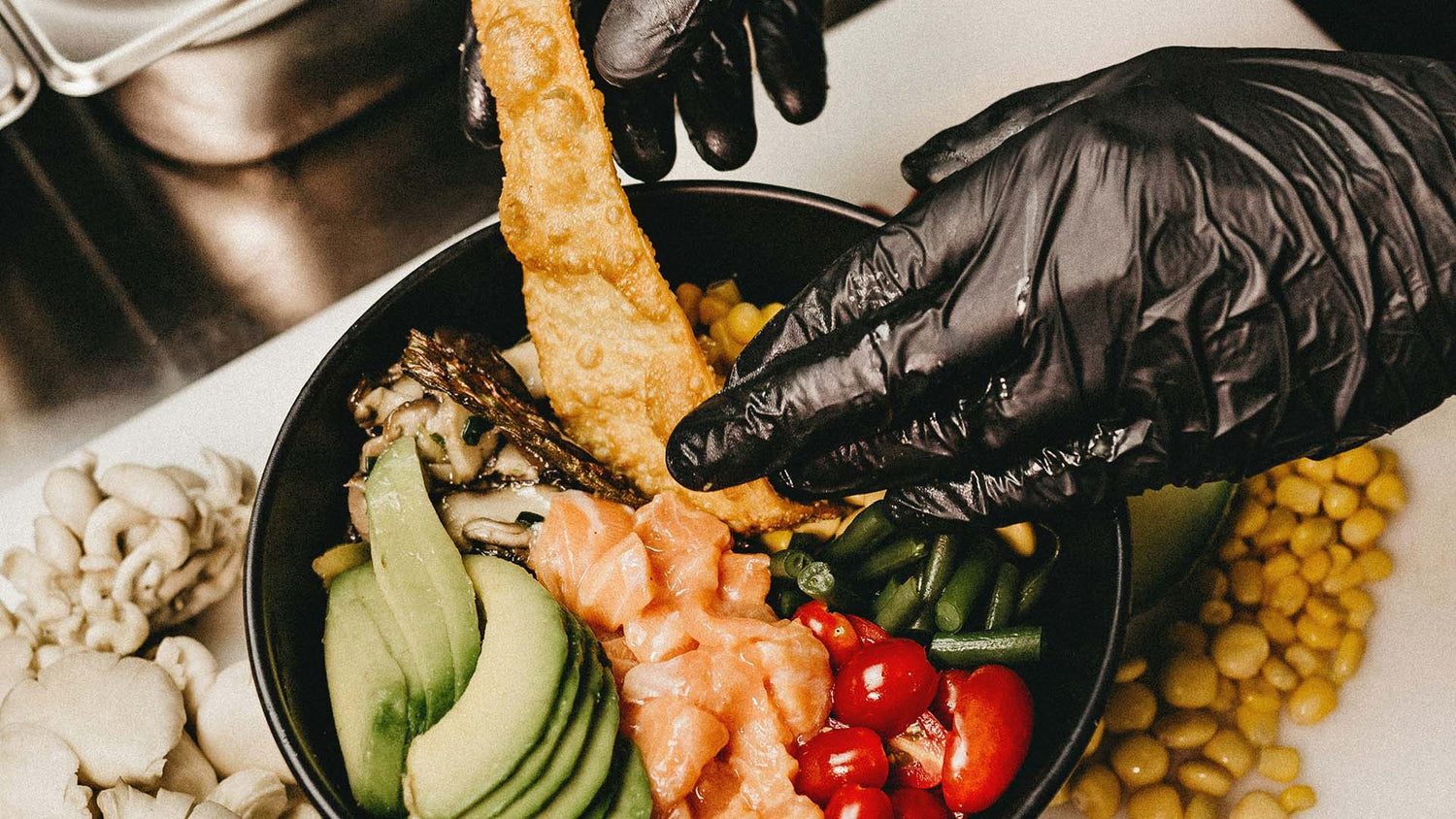 person preparing a dish while wearing black disposable gloves