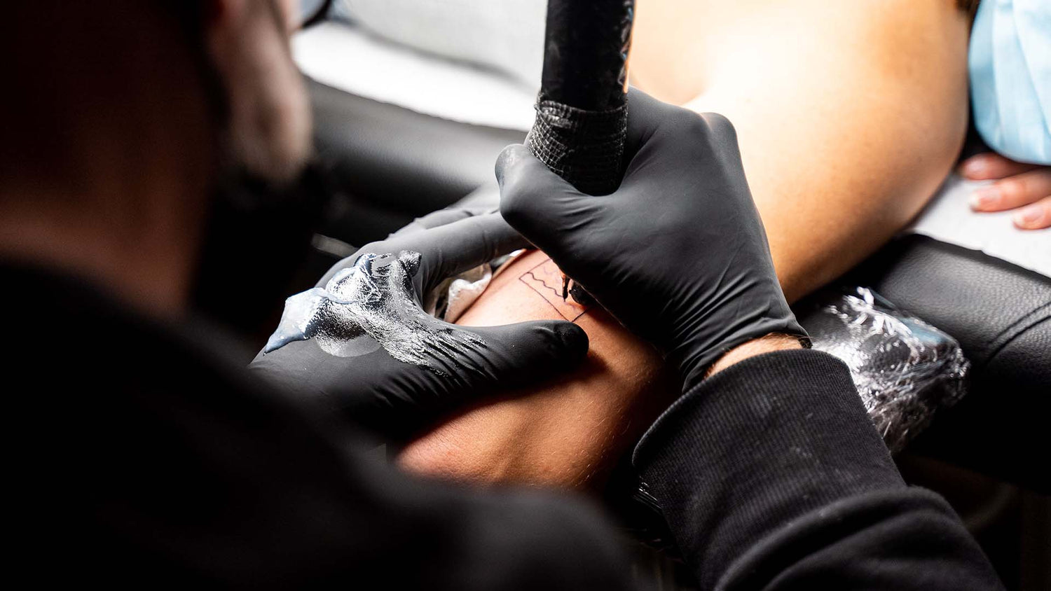 a tattoo artists wearing black disposable gloves