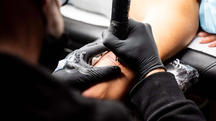 a tattoo artists wearing black disposable gloves