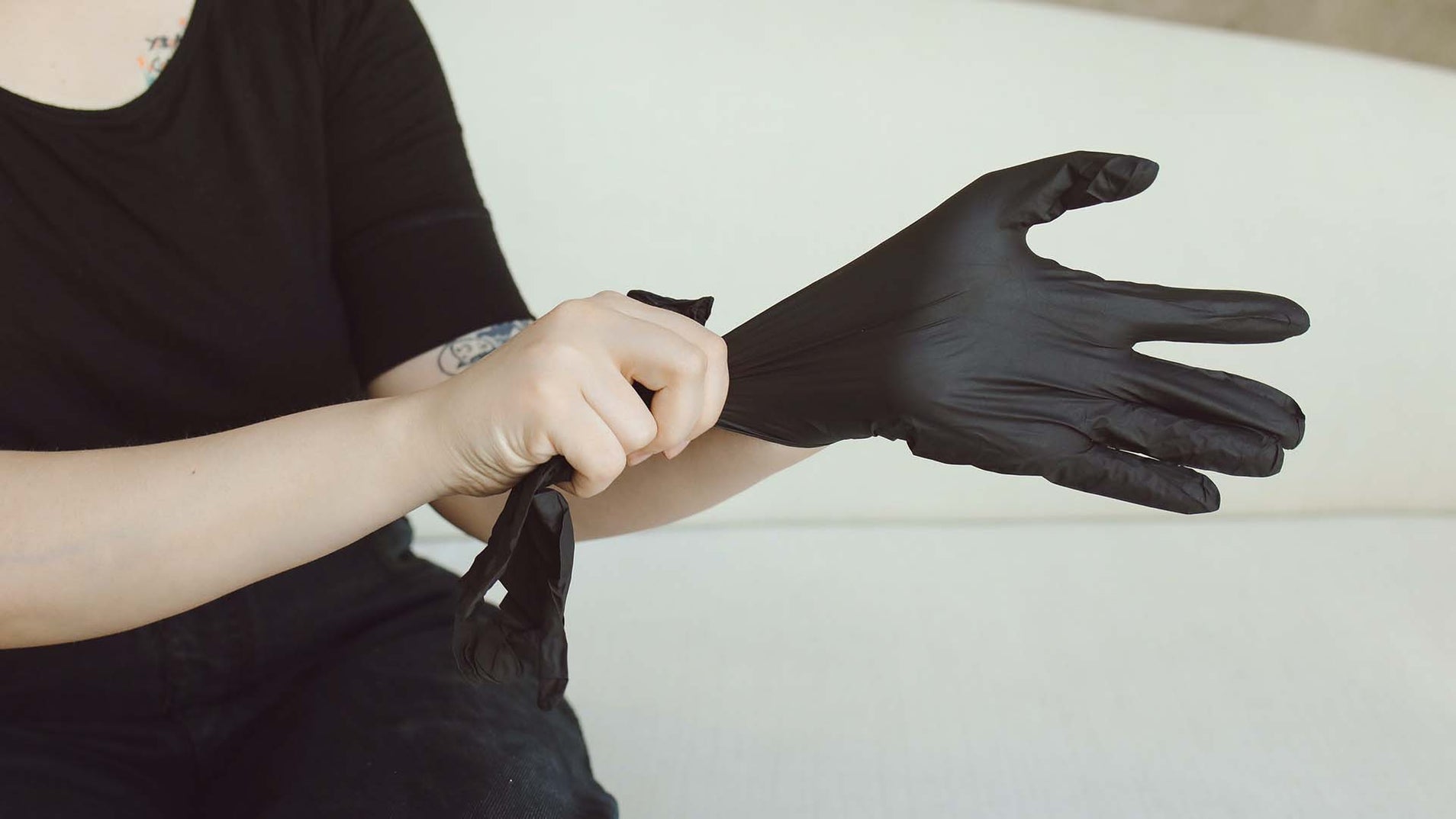 person donning a set of black nitrile gloves