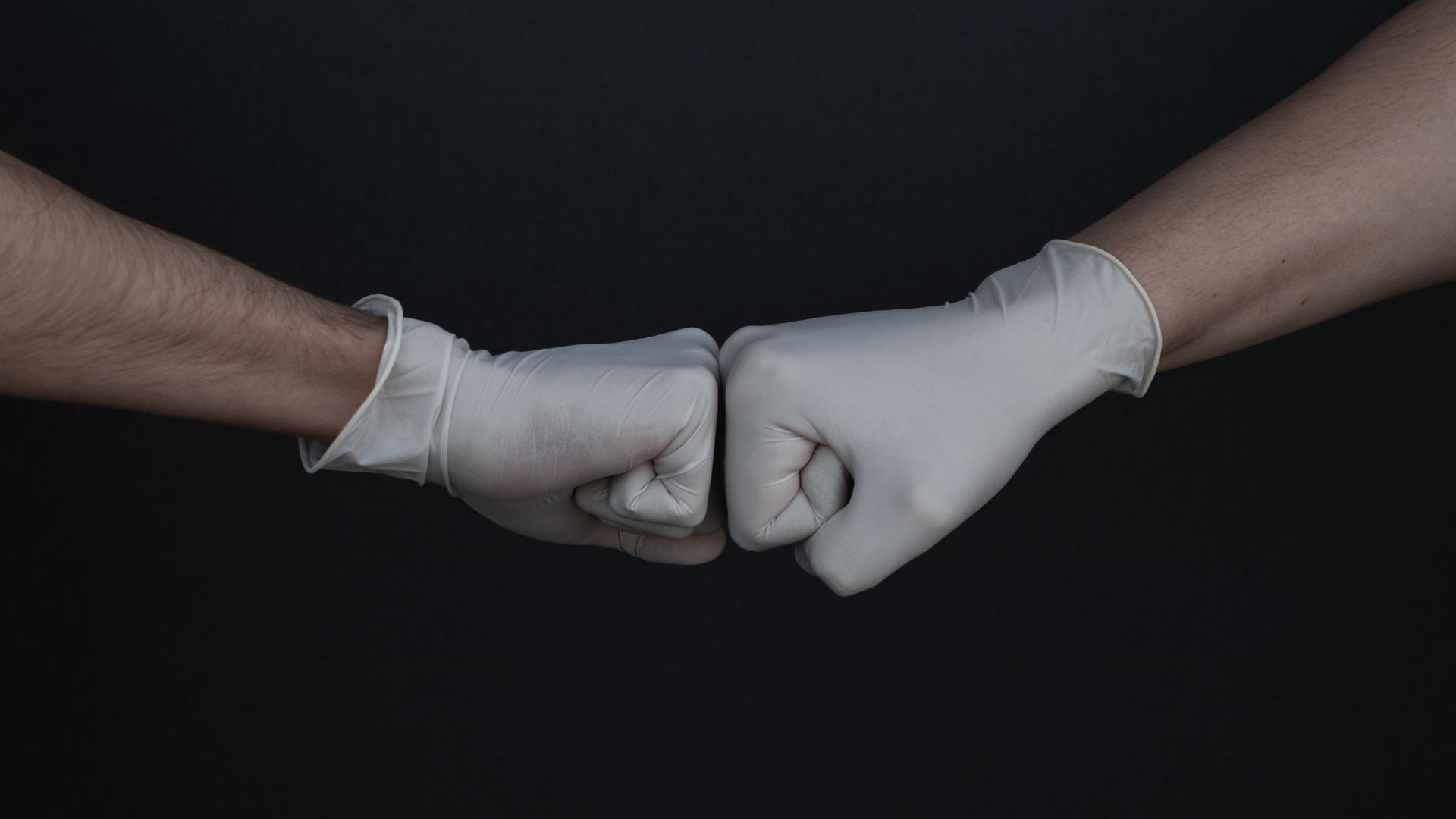 two hands in white gloves, engage in a fist bump gesture