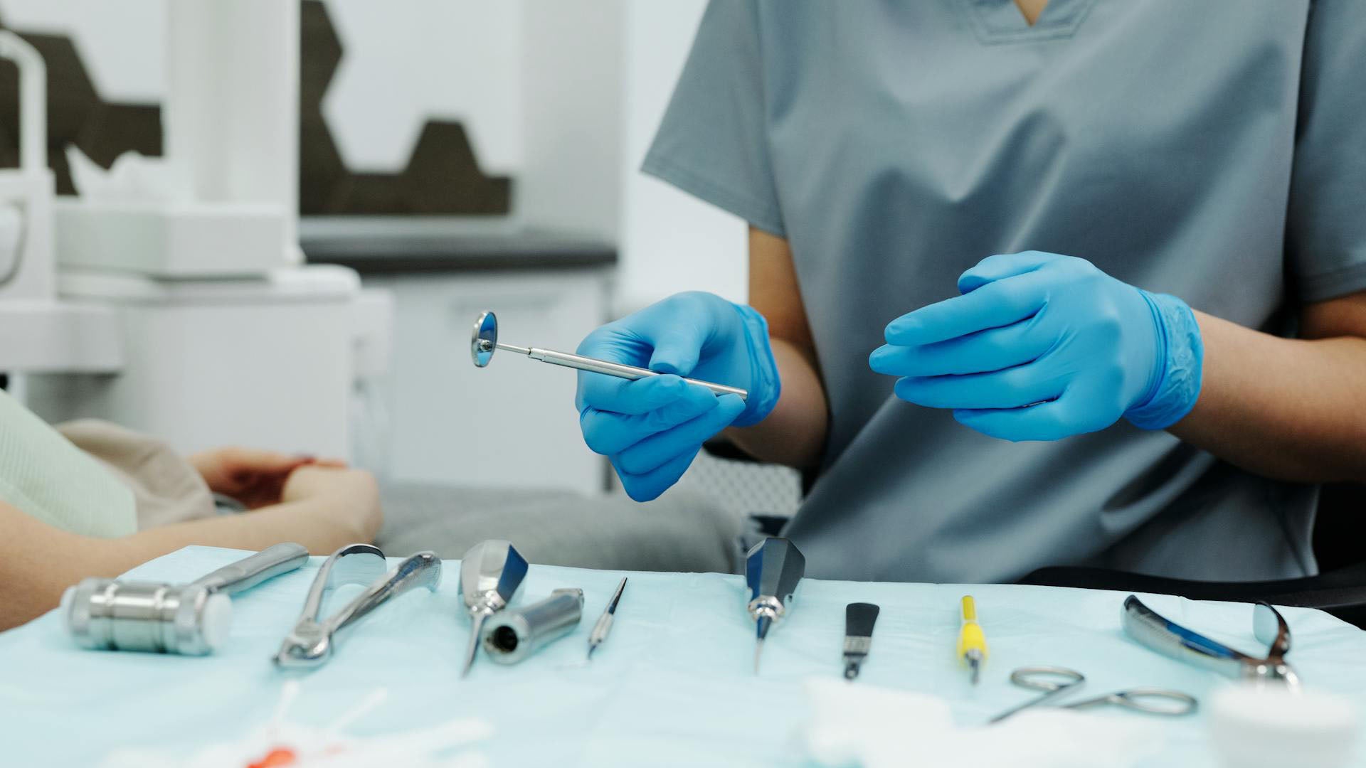 a dentist in blue nitrile gloves holding a dental equipment