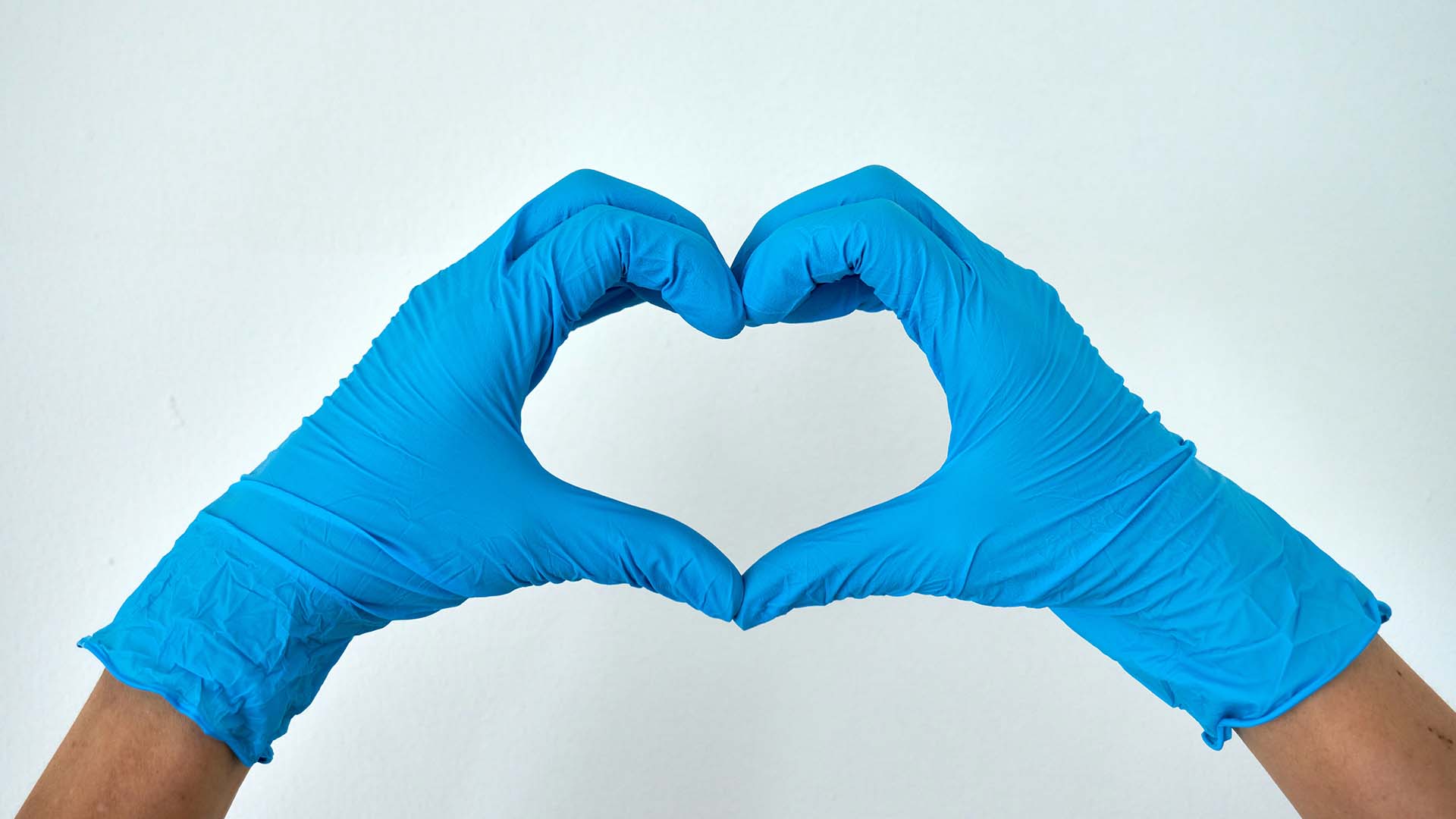 Hands in blue disposable gloves making a heart