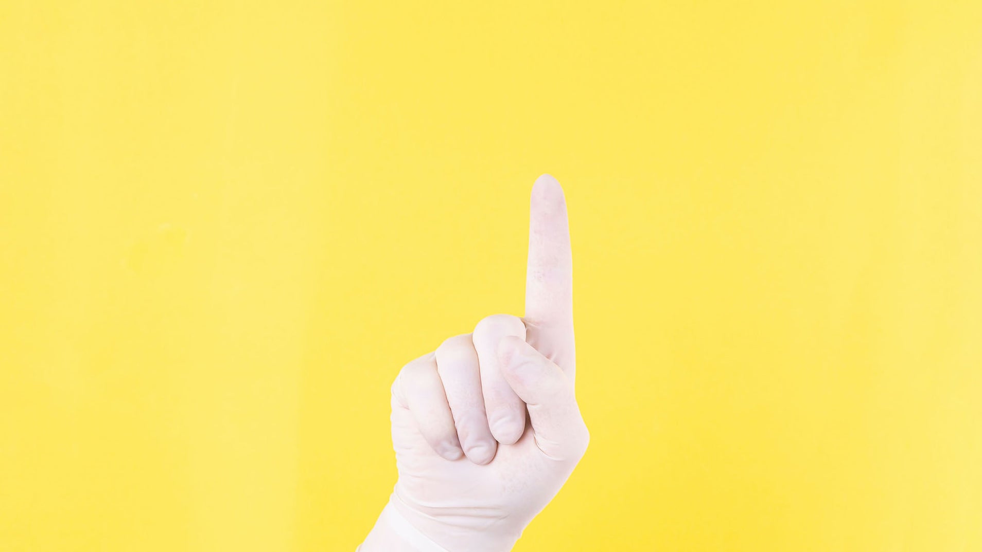 hand in white glove on yellow background with one finger raised