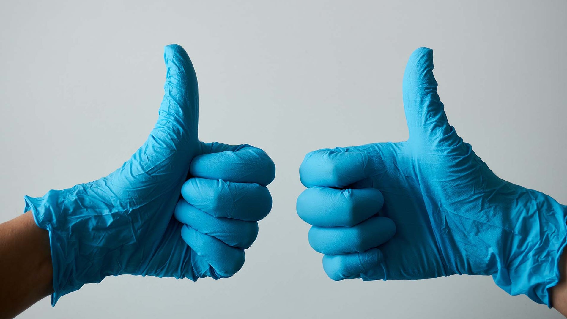 Hands wearing blue nitrile gloves giving two thumbs up