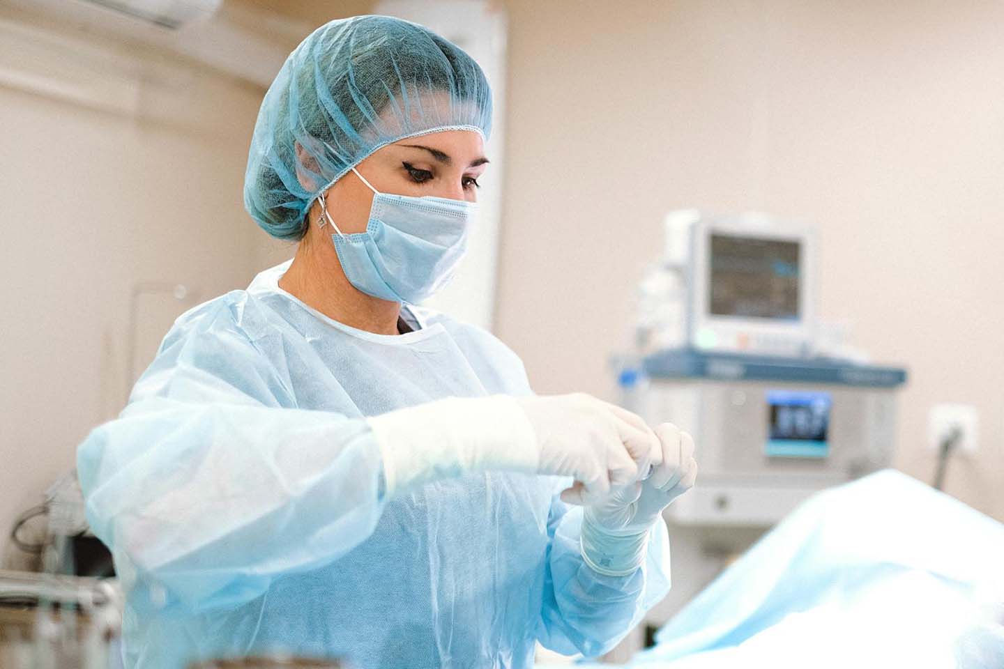 A surgeon preparing for an operation and wearing a sterile surgical gown, cap and sterile gloves.