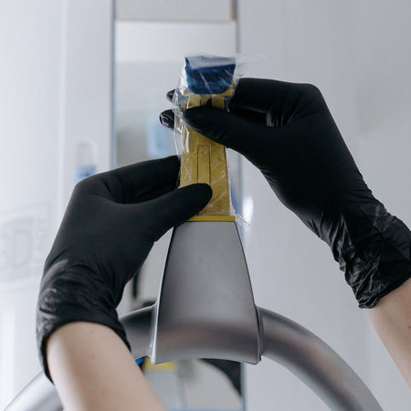 person wearing black gloves and holding a dental equipment