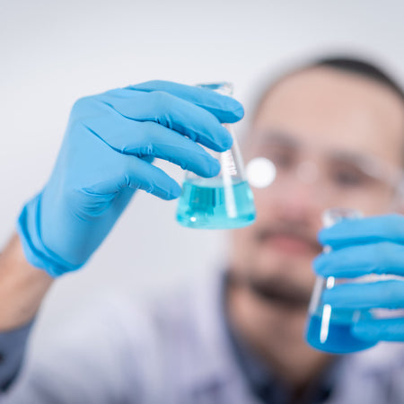 person wearing blue gloves and holding glass flasks