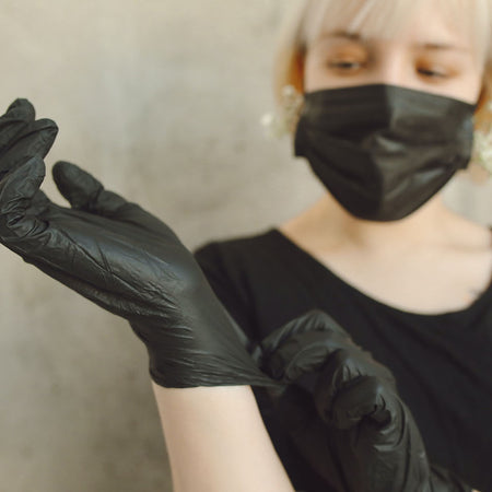 woman putting on black disposable gloves