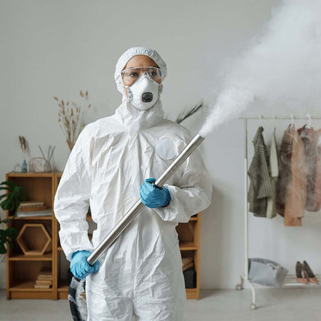 woman fumigating a room while wearing a complete personal protective equipment