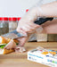person wearing disposable clear polyethylene gloves while slicing a meal