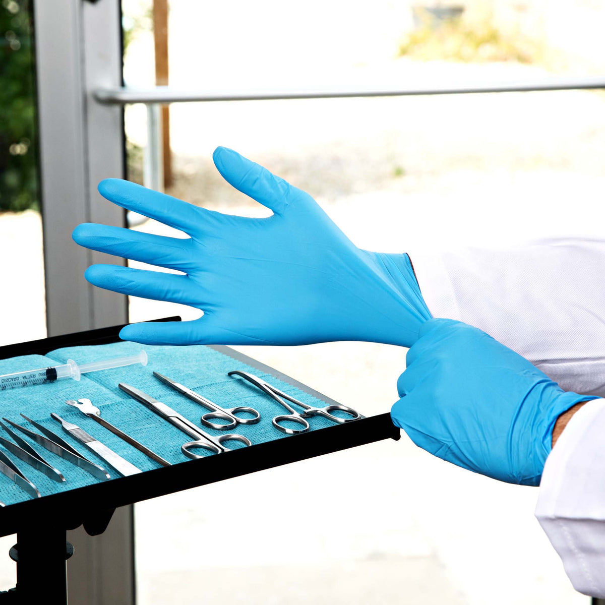 a health personnel donning a pair of blue nitrile gloves in preparation for a medical examination