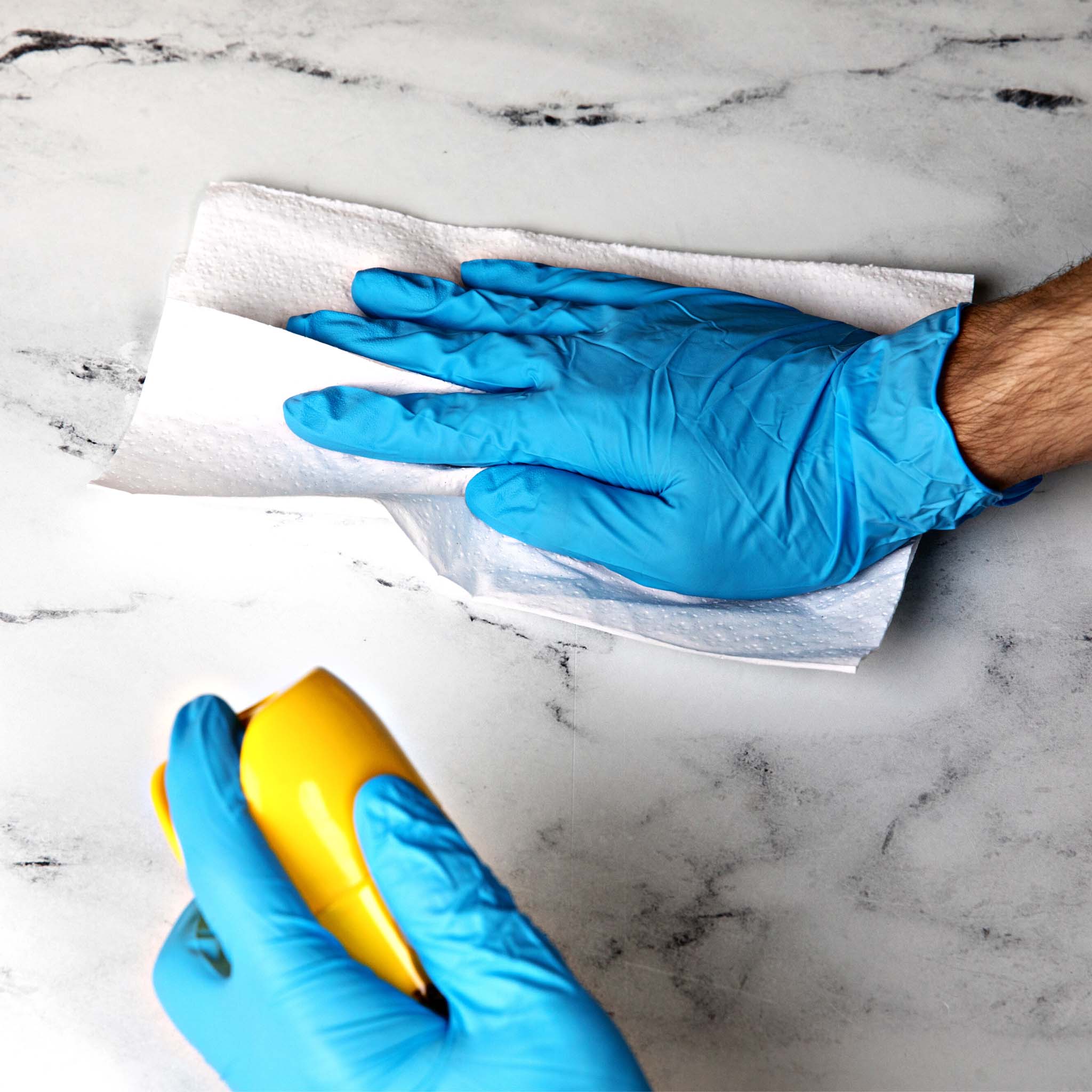 a person in blue nitrile gloves cleaning up a surface