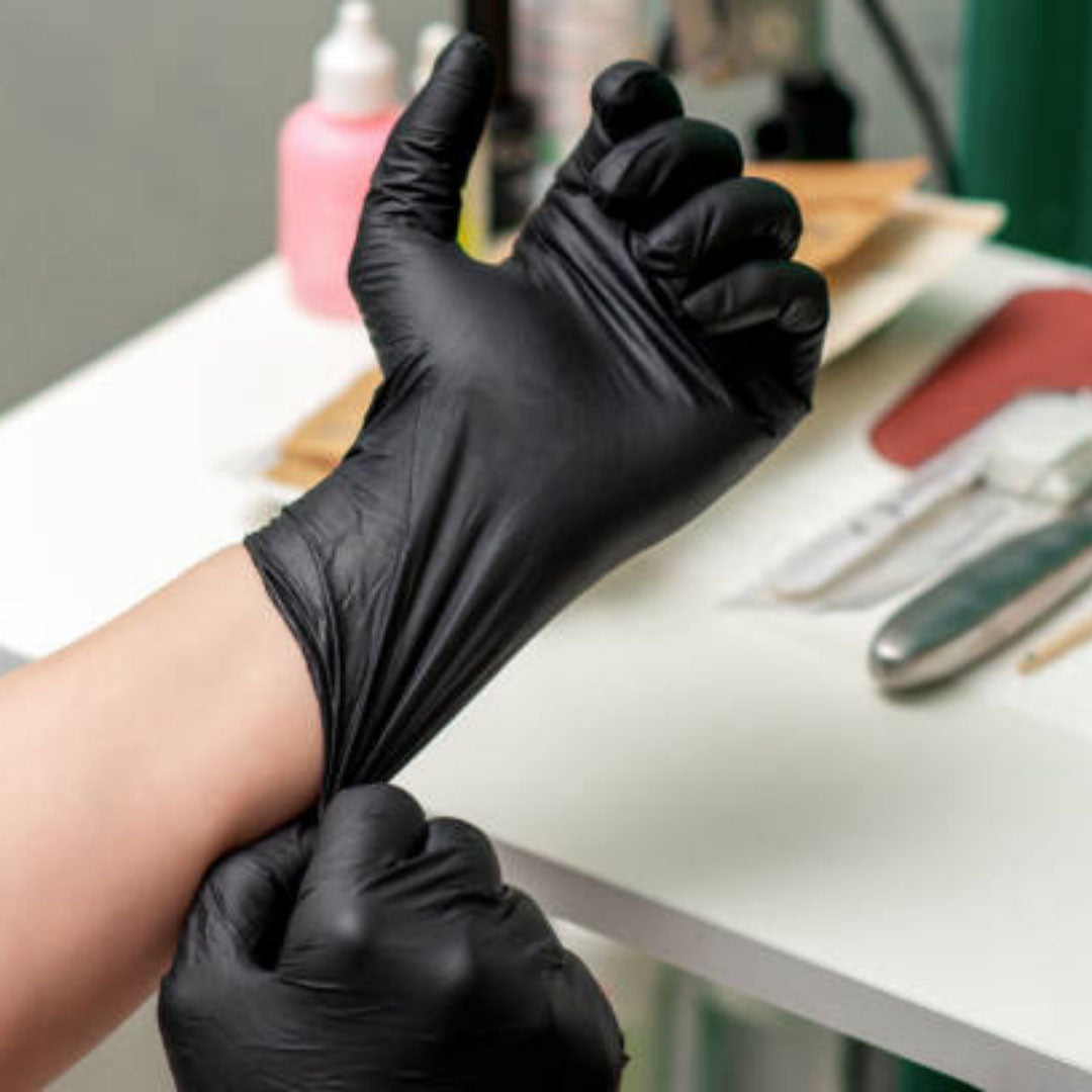 person donning black latex gloves inside the hospital